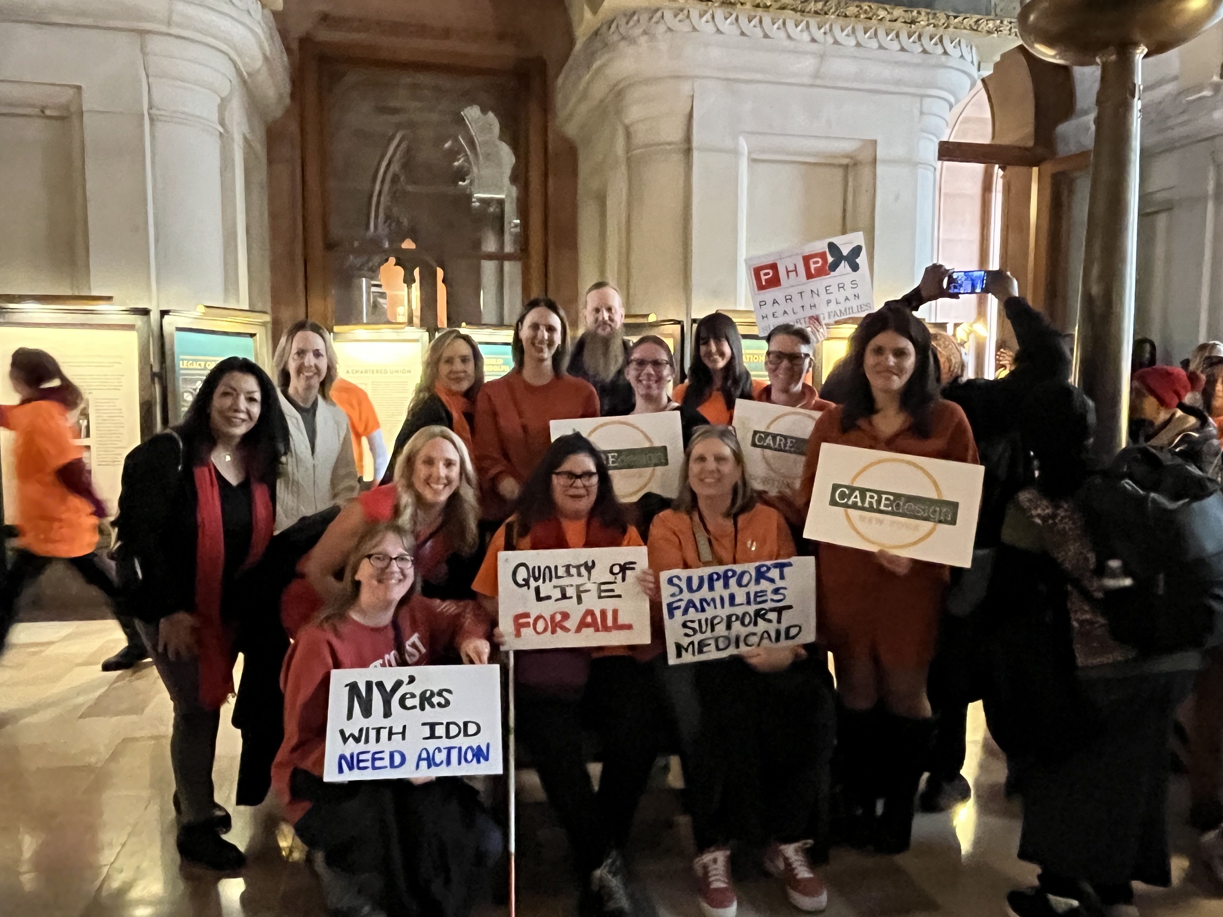 NYDA Rally event, members of Care Design New York hold signs in New York State Capitol building