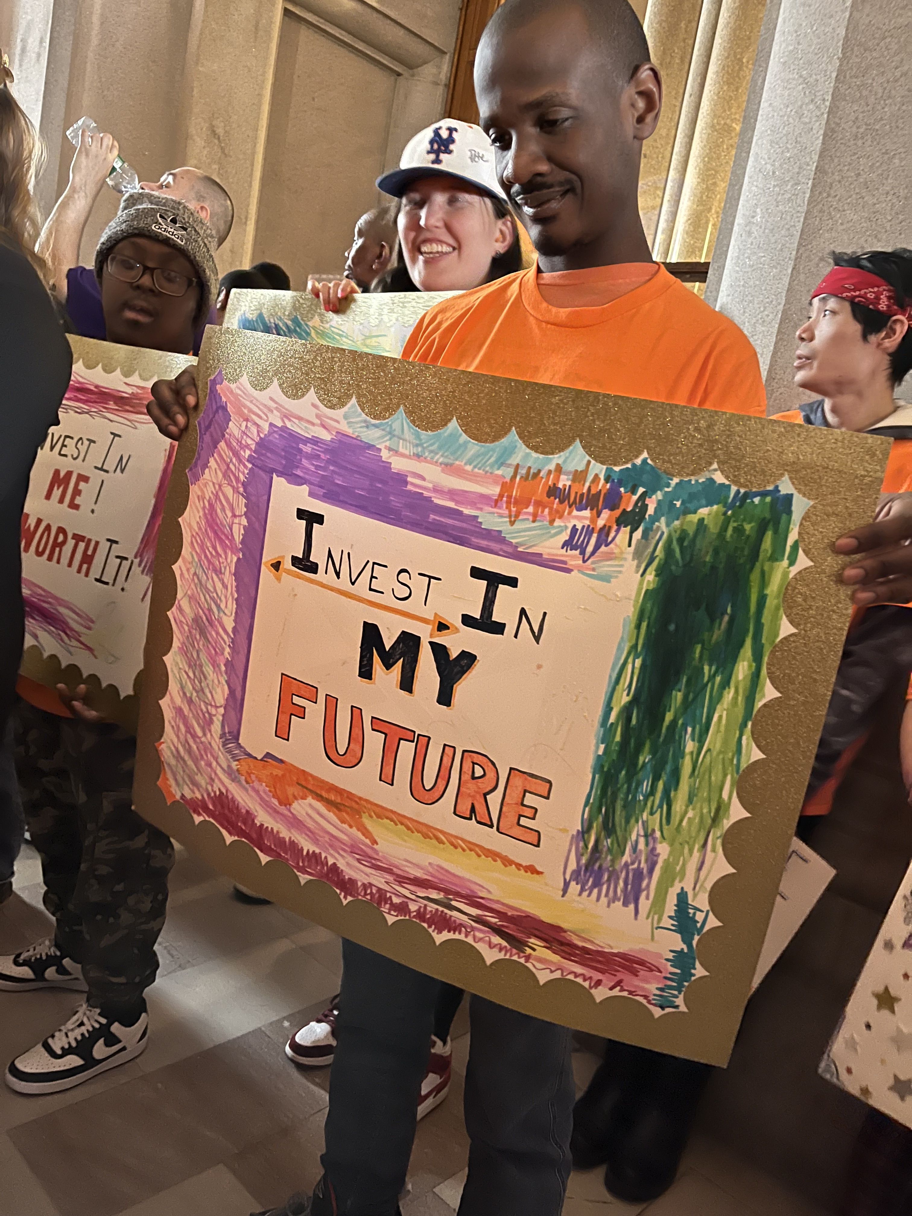 Man holding an invest in my future sign at NYDA Rally