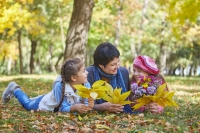 Loving mother and two daughter in autumn park. One daughter with a disability with Down syndrome.