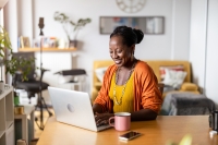 African American woman sits at her desk working on her laptop