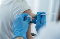 Cropped shot of a doctor wearing blue gloves giving an unidentified person a flu shot.