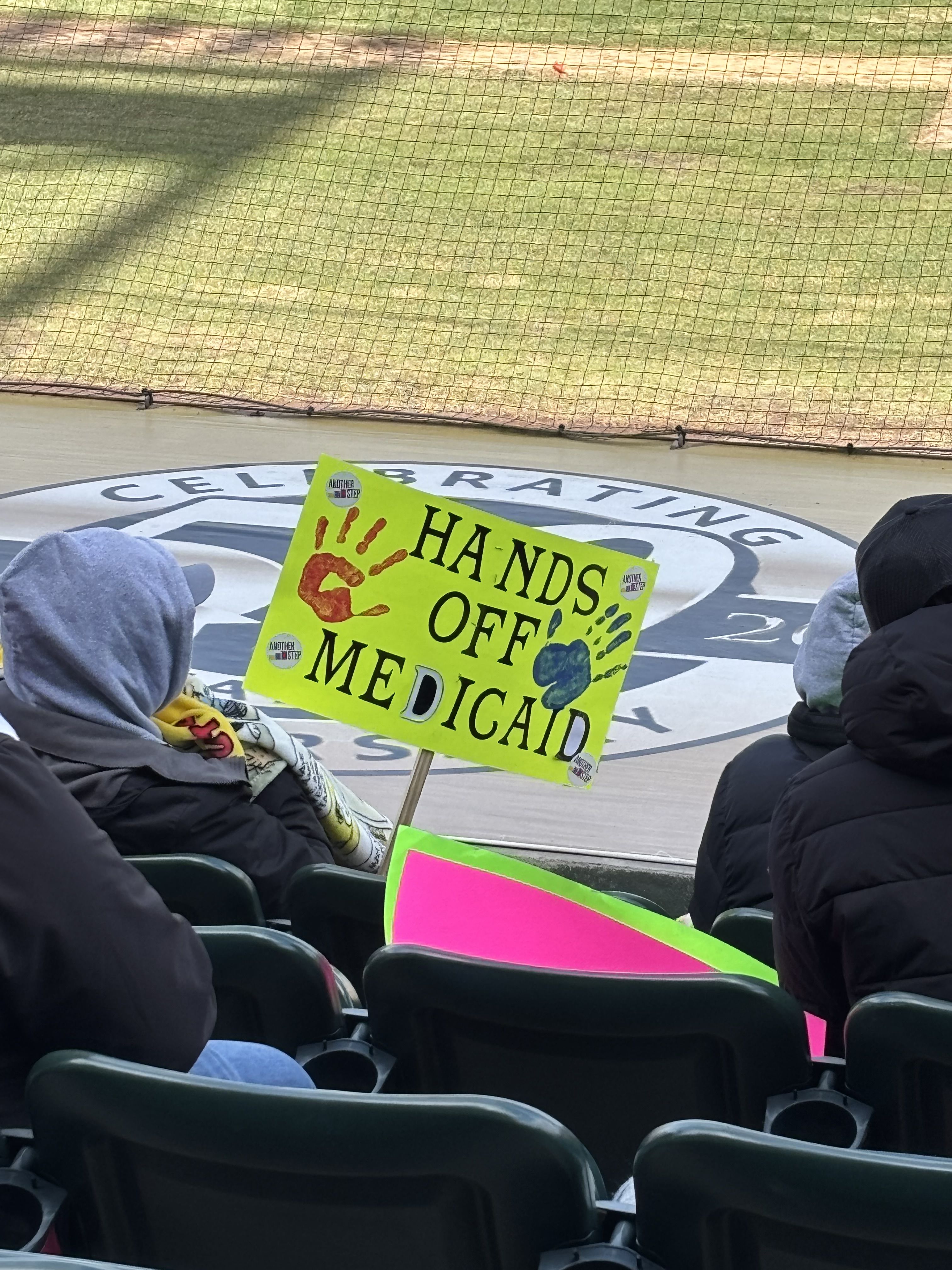 Neon yellow sign that reads Hands off Medicaid