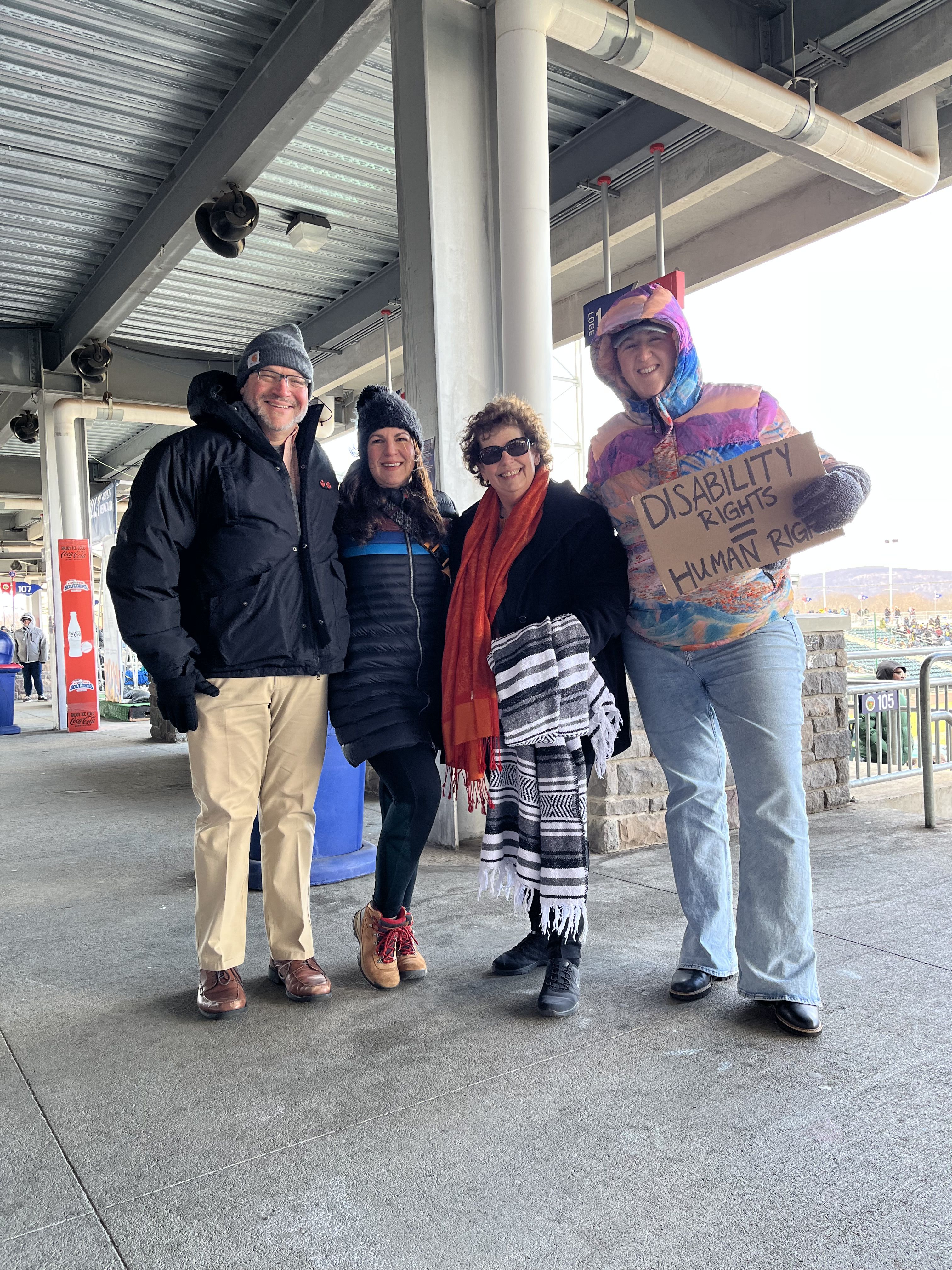 team members from Care Design New York at NY Boulders Stadium. One holding a sign that says disability rights = human rights