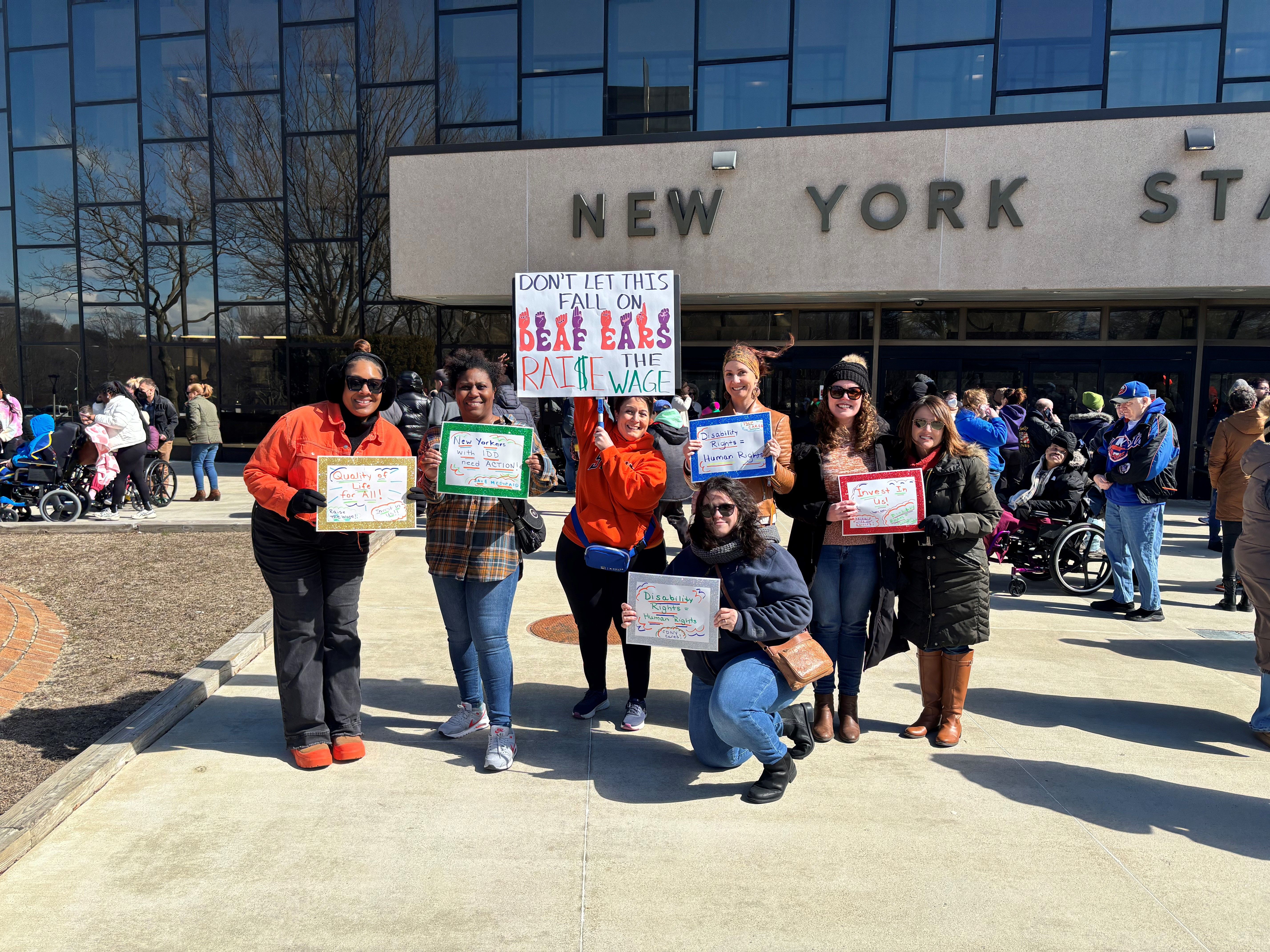 team members from Care Design New York at New York State building holding signs